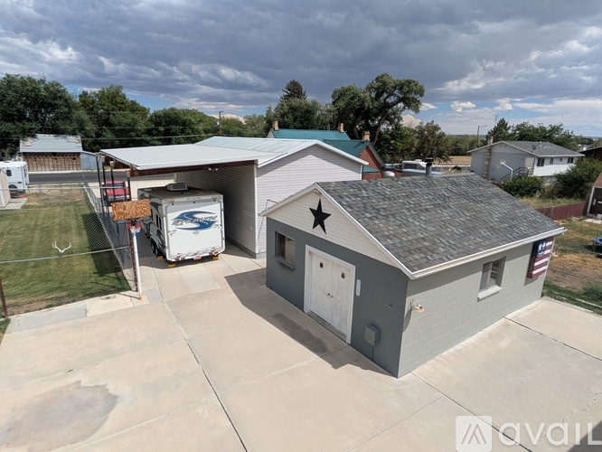A grey building with a black star on the roof is surrounded by a concrete driveway.