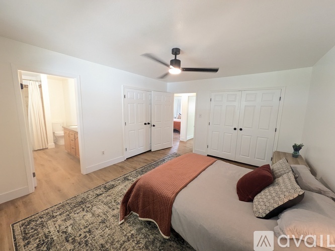 A bedroom with a bed in the center and a fan on the ceiling.