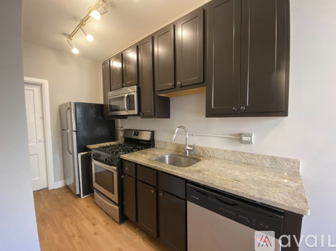 A kitchen with black cabinets and a granite countertop.
