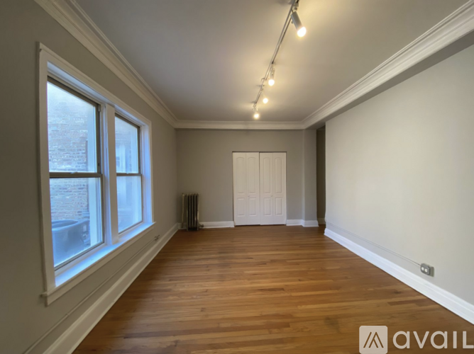 A room with wooden floors and a window overlooking a brick building.