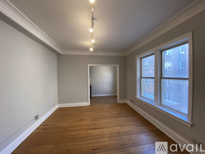 A room with wooden floors and a window overlooking a cityscape.