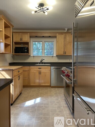 A kitchen with wooden cabinets and a stainless steel refrigerator.