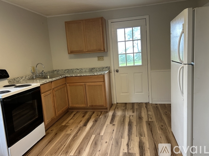 A kitchen with wooden floors and a white refrigerator.