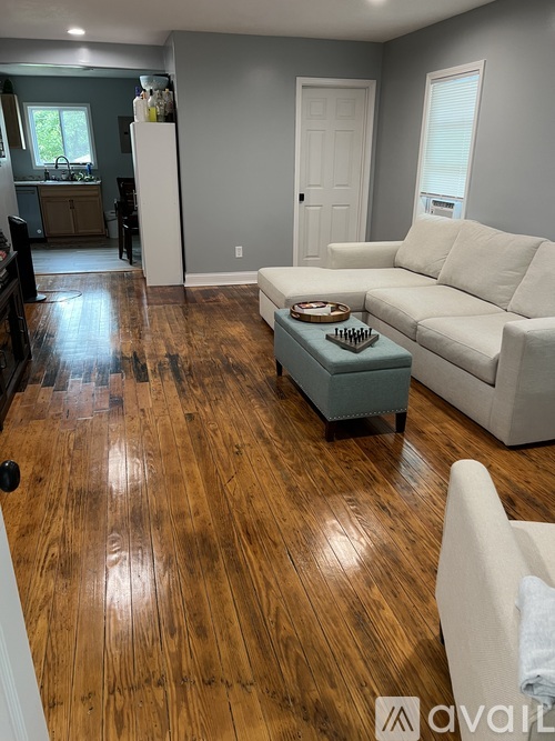 A living room with a white couch and a wooden floor.