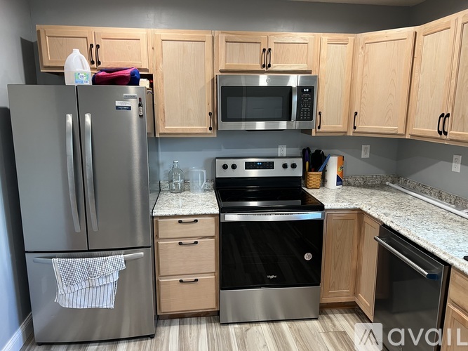 A kitchen with a stainless steel refrigerator, microwave, oven, and cabinets.