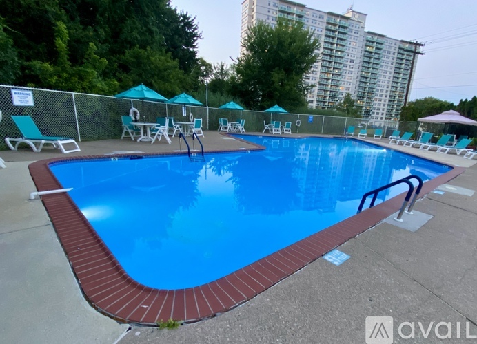A large outdoor swimming pool surrounded by a fence and lounge chairs.