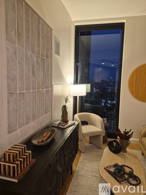 A modern living room with a large window overlooking the city at night.