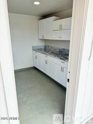 A kitchen with white cabinets and a marble countertop.