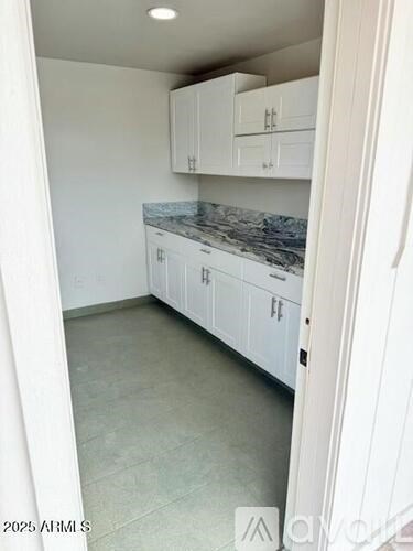 A kitchen with white cabinets and a marble countertop.