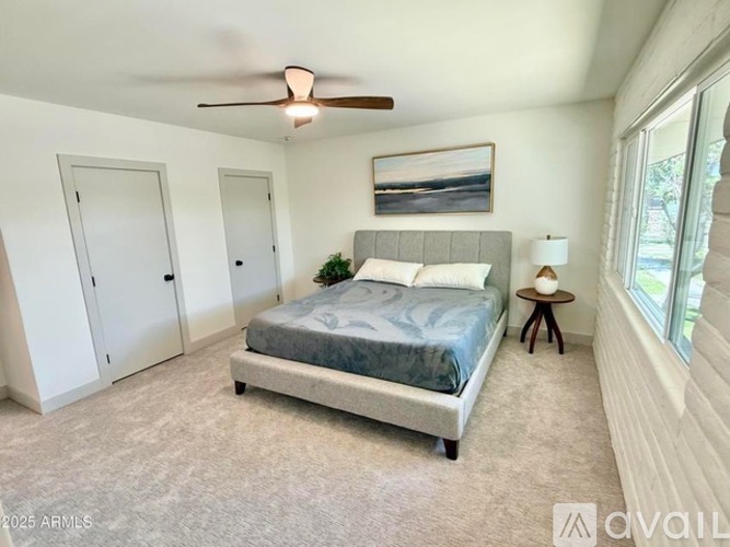 A bedroom with a bed, a ceiling fan, and two doors.