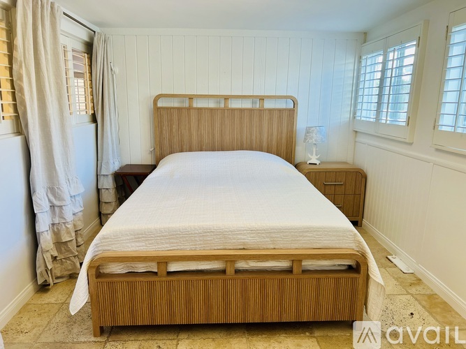 A bedroom with two beds and a window with curtains.