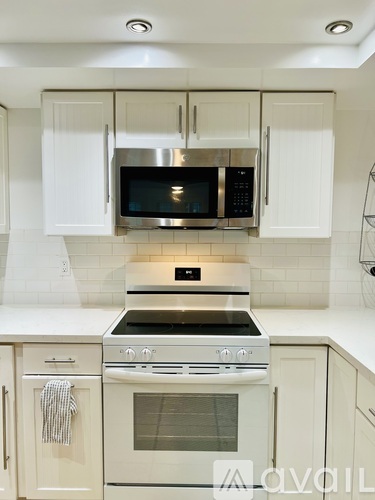 A kitchen with white cabinets and a stainless steel microwave above the stove.