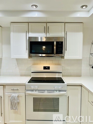 A kitchen with white cabinets and a stainless steel microwave above the stove.