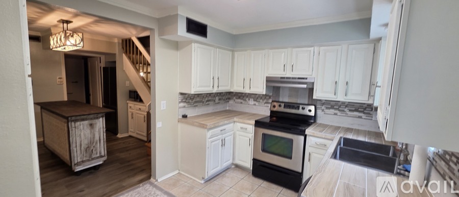 A kitchen with white cabinets and a black stove top oven.