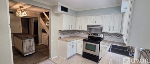 A kitchen with white cabinets and a black stove top oven.