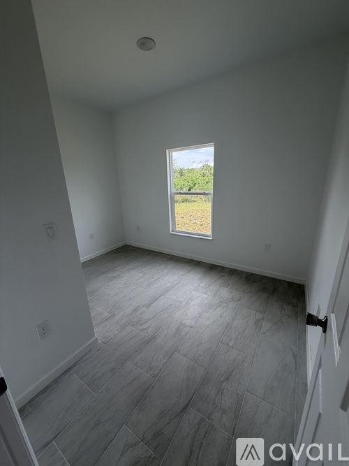 A room with a window showing a view of a grassy field.