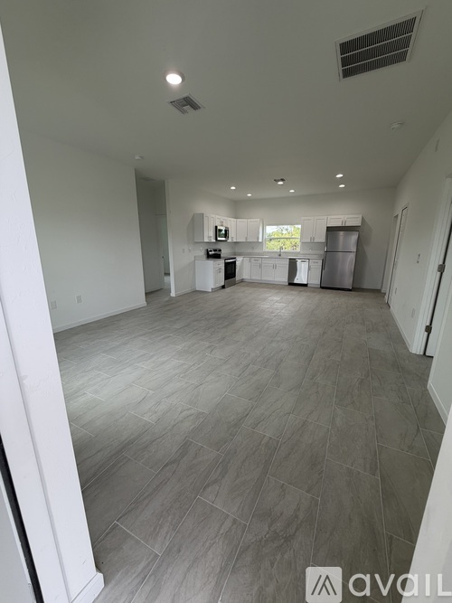 A spacious kitchen and living room with white cabinets and a grey floor.