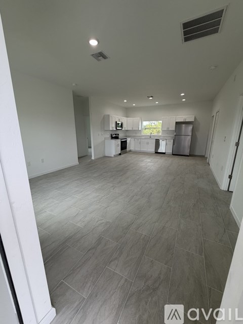 A spacious kitchen and living room with white cabinets and a grey floor.