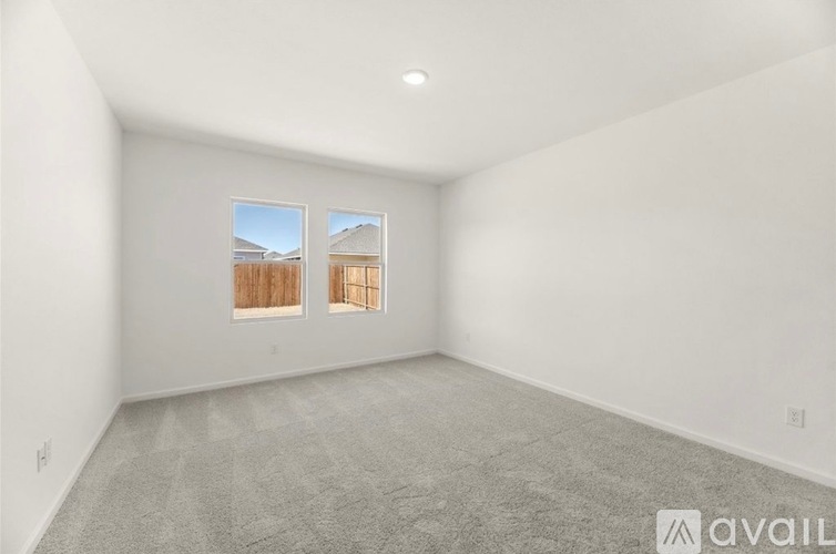 A spacious room with a carpeted floor and two windows.