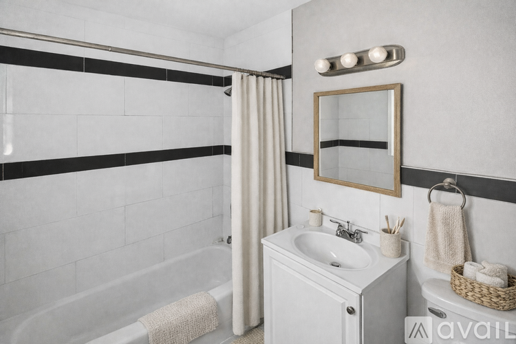 A white bathroom with a white tub, sink, and a mirror.