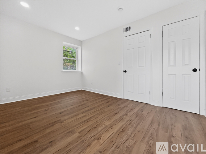 A room with wooden flooring and two white doors.