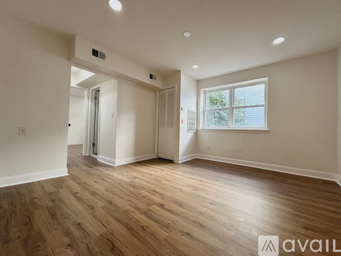 A spacious room with wooden flooring and a window.