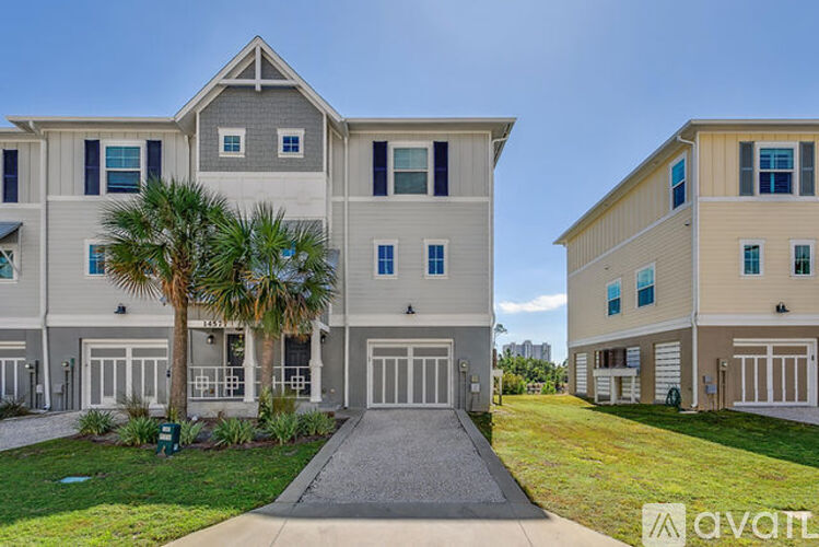A modern two-story apartment building with a palm tree in front.