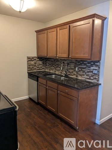 A kitchen with brown cabinets and a black dishwasher.