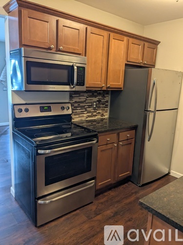 A kitchen with wooden cabinets and a stainless steel refrigerator.
