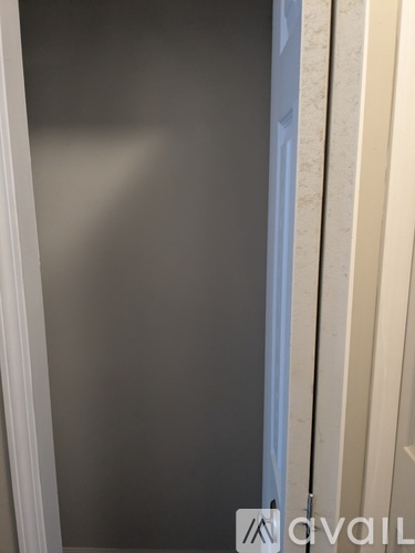 A white door is open to a room with a grey wall.