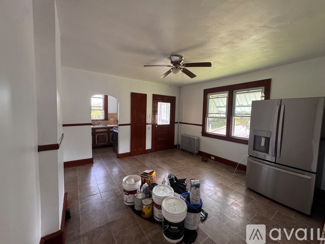 A kitchen with a refrigerator, a fan, and a table with chairs.