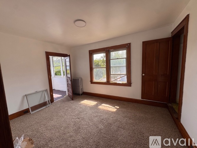 A room with a carpeted floor, two windows, and a door.
