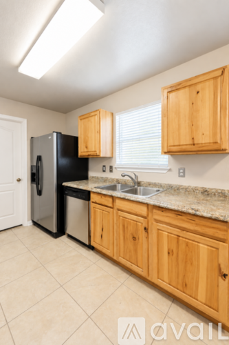 A kitchen with wooden cabinets and a black fridge.