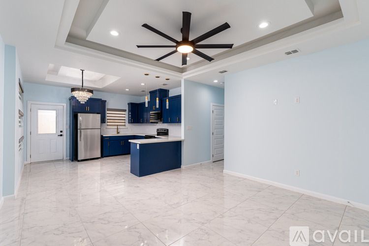 A spacious kitchen with a blue island and a ceiling fan.
