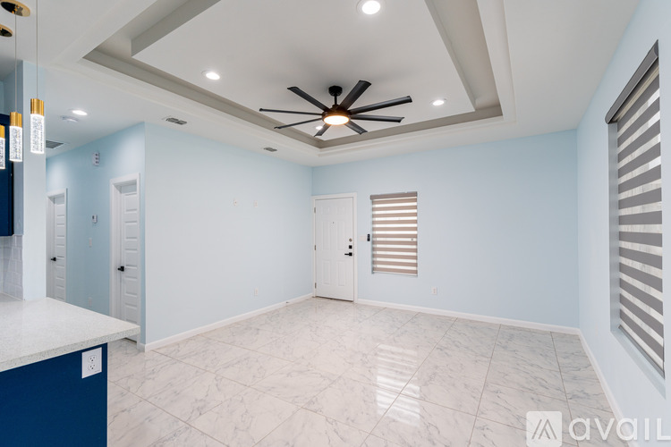 A spacious room with a ceiling fan and marble flooring.