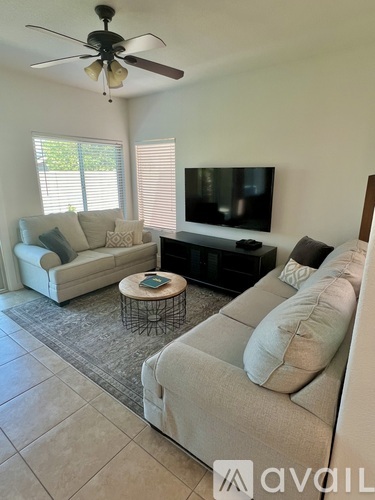 A living room with a couch, a coffee table, and a television.