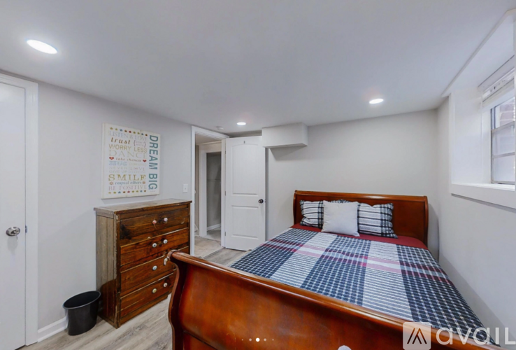 A bedroom with a bed, dresser, and a poster on the wall.
