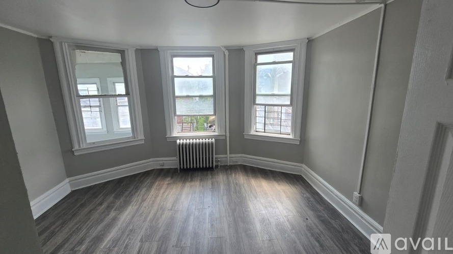 A room with wooden floors and three windows.