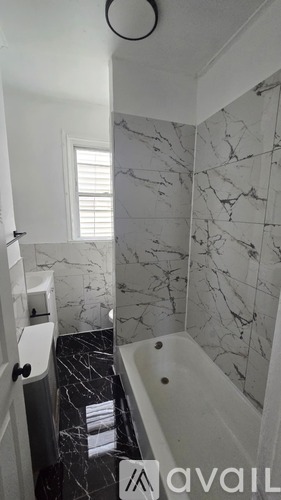 A bathroom with marble tiles and a bathtub.