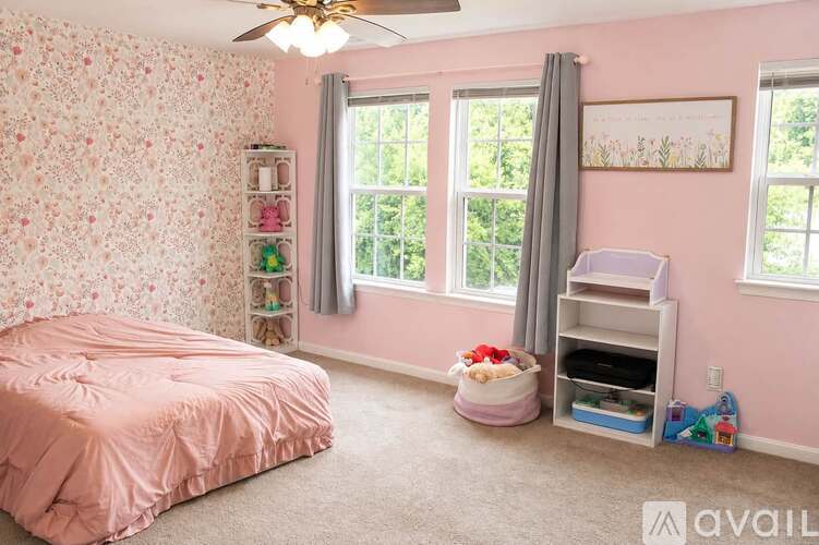 A bedroom with a pink bed and a fan on the ceiling.