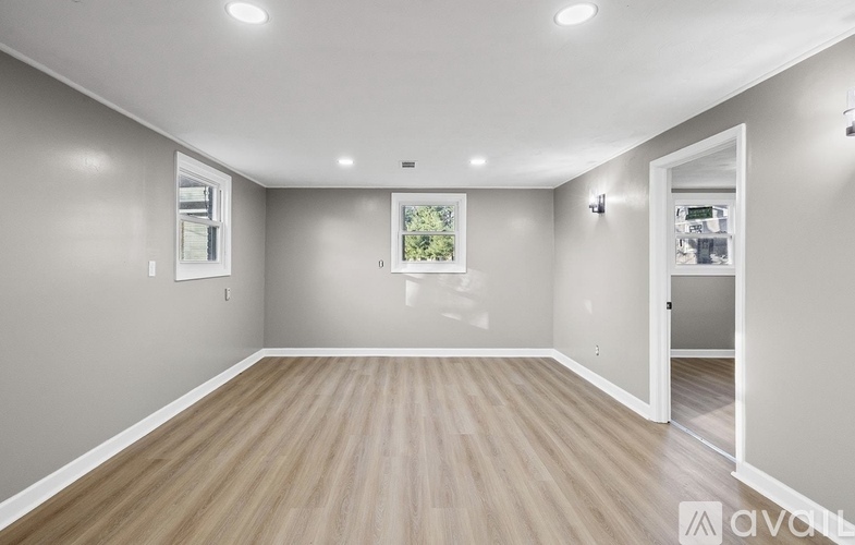A spacious room with wooden flooring and white walls.