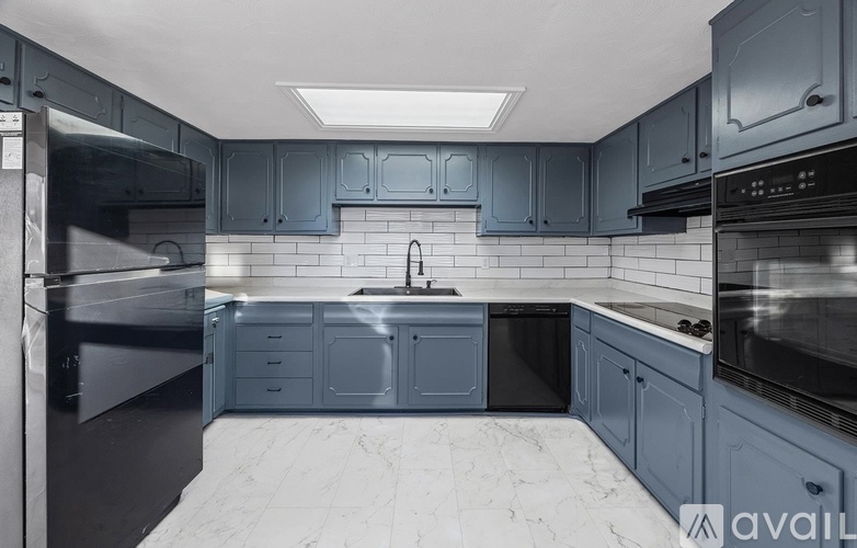 A modern kitchen with dark cabinets and a marble floor.