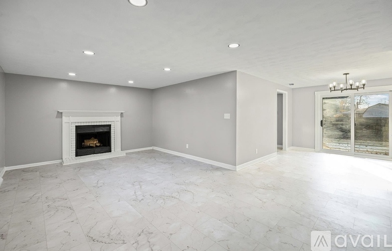 A spacious living room with a fireplace and a chandelier.