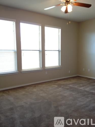 A room with a carpeted floor, a ceiling fan, and a window with blinds.