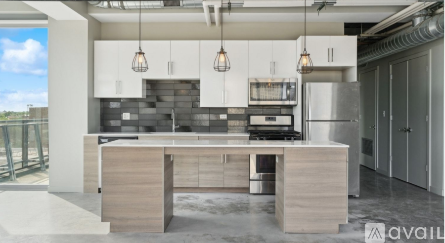 A modern kitchen with a large island and pendant lights.
