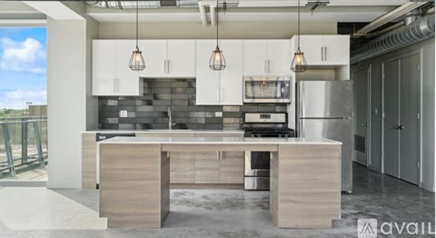 A modern kitchen with a large island and pendant lights.