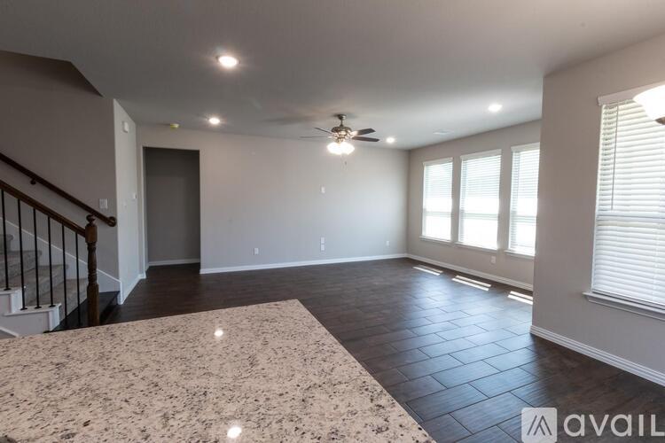 A spacious room with a carpeted floor and a staircase on the left side.