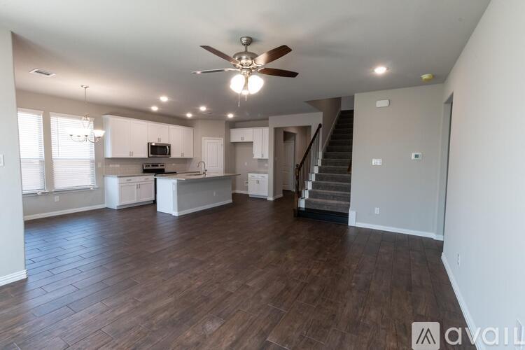 A spacious living room with wood flooring and a staircase leading to another room.
