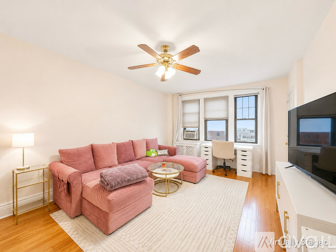 A living room with a pink couch and a ceiling fan.