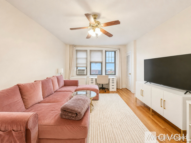 A living room with a red couch and a ceiling fan.